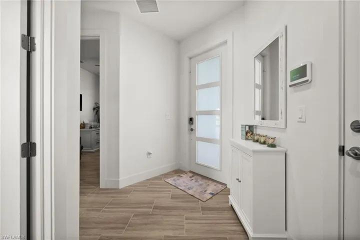 Doorway to outside with visible vents, baseboards, and wood finish floors