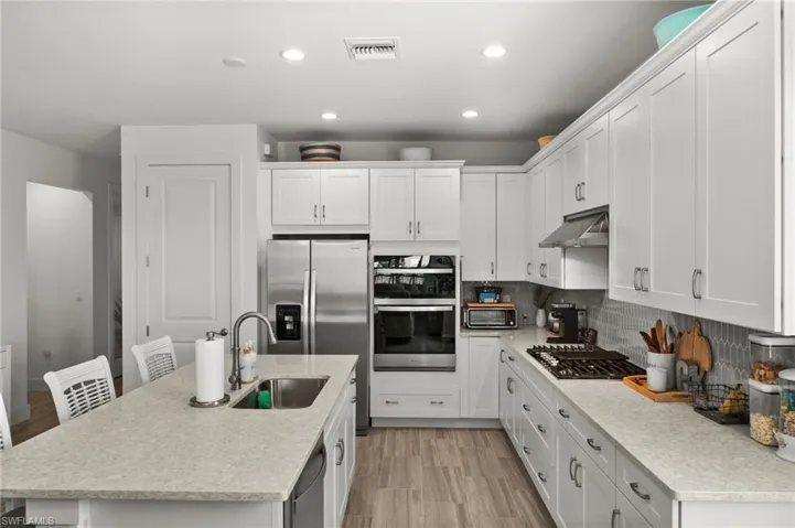 Kitchen with visible vents, a sink, light countertops, appliances with stainless steel finishes, and under cabinet range hood