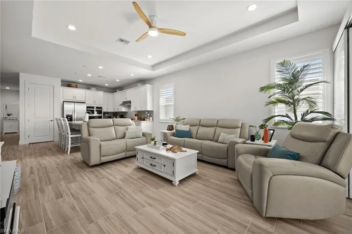 Living room featuring visible vents, a raised ceiling, recessed lighting, and a ceiling fan