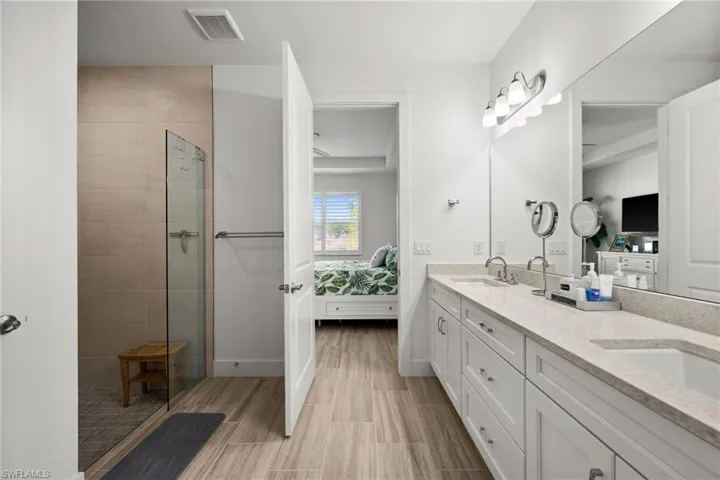 Ensuite bathroom featuring a shower stall, ensuite bathroom, visible vents, and a sink