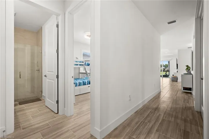 Hallway with visible vents, baseboards, and wood finish floors