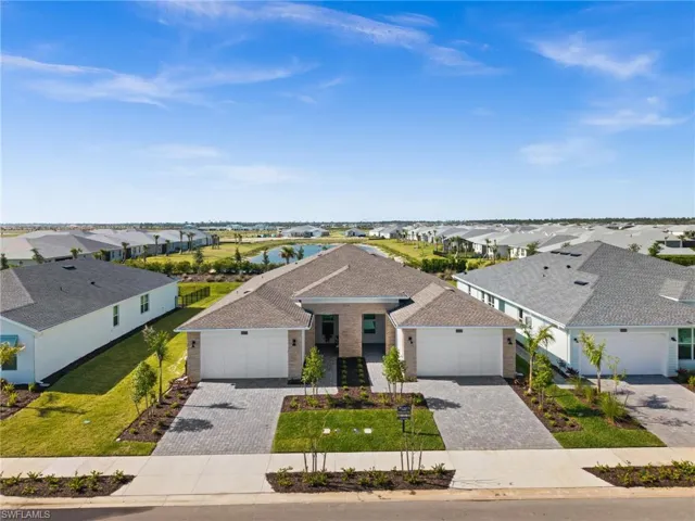 View of front facade featuring a front yard, a residential view, decorative driveway, and roof with shingles