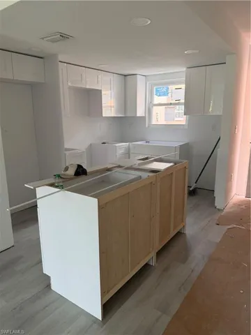 Kitchen featuring a kitchen island, light wood finished floors, and white cabinets
