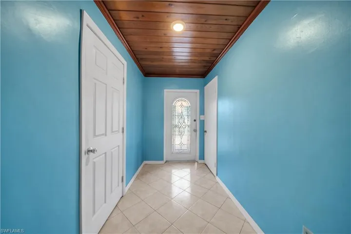 Entryway featuring a decorative glass front door, wood-paneled ceiling, recessed lighting, and diagonal tile flooring
