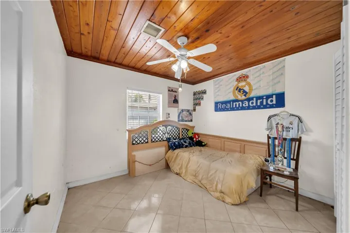 Room featuring a wood-panel ceiling, ceiling fan, and tile flooring