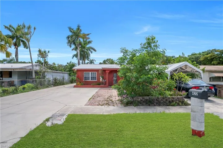 Red exterior with white-framed windows, a brick paver walkway, and a concrete driveway