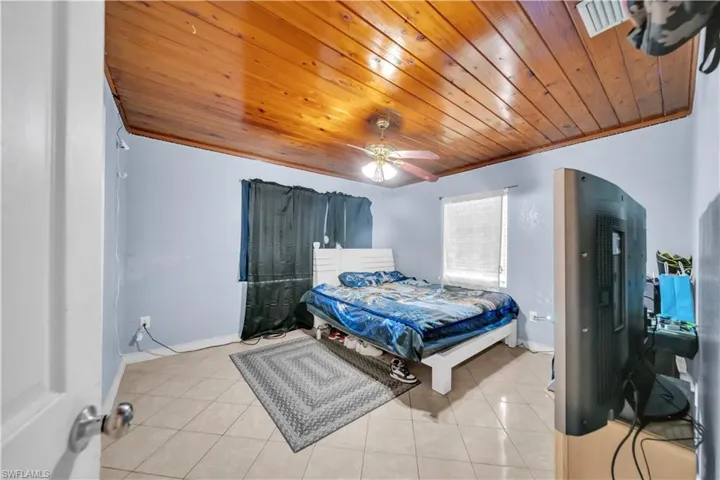 Room featuring a wood-panel ceiling, light blue walls, and neutral-toned tile flooring