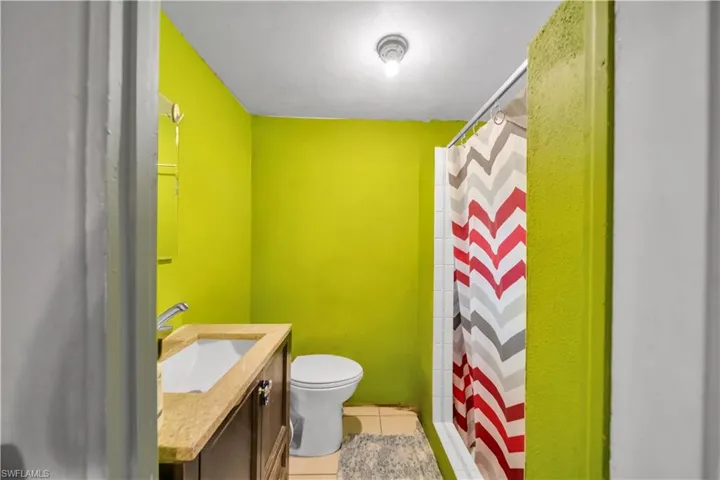 Bathroom featuring a vanity with an integrated sink, a commode, and a shower with a tiled surround