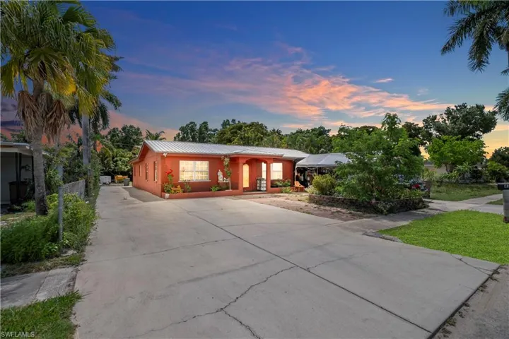 Red stucco exterior with a metal roof and a spacious concrete driveway