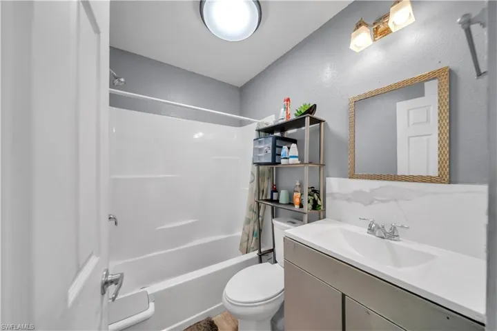 Full bathroom featuring a white tub/shower combination, a vanity with an integrated sink, and a wall-mounted mirror