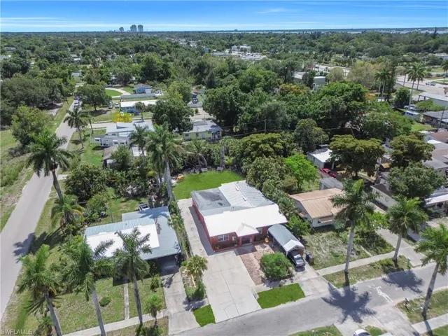 Property featuring mature palm trees, a paved driveway, and a covered carport