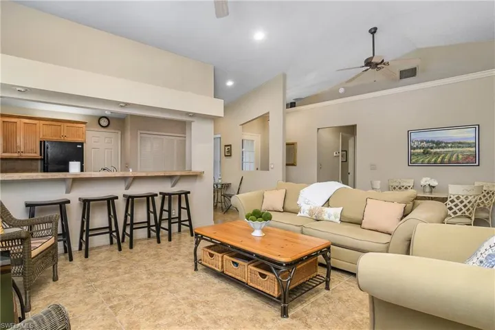 Living area with ceiling fan, lofted ceiling, crown molding, recessed lighting, and light tile patterned floors