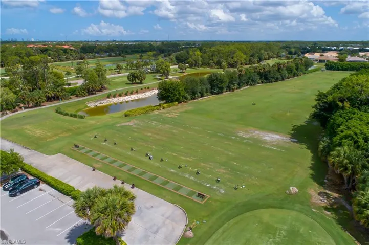 Drone / aerial view of a nearby body of water, a golf club, and a tree filled landscape
