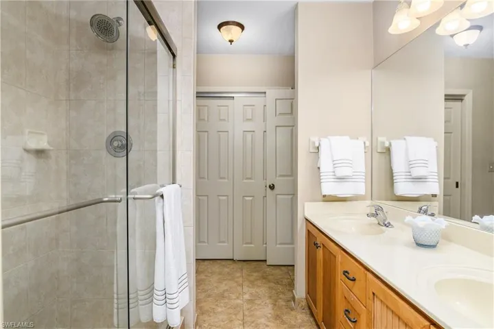 Full bathroom with a stall shower, double vanity, and tile patterned flooring