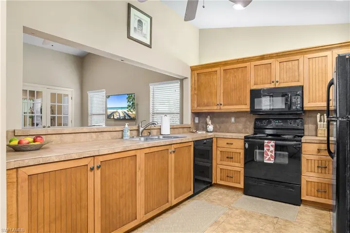 Kitchen featuring black appliances, a sink, high vaulted ceiling, tasteful backsplash, and a ceiling fan