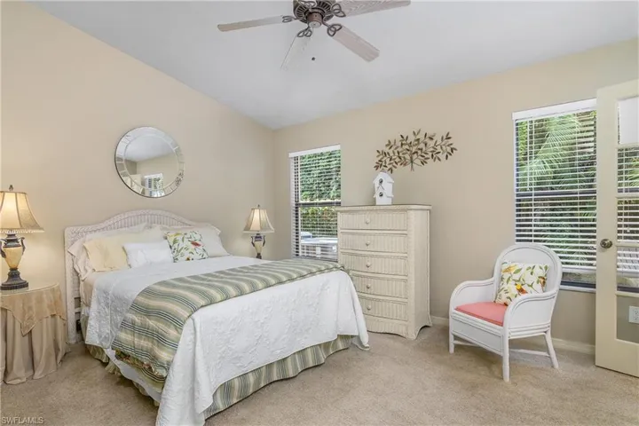 Bedroom with multiple windows, light carpet, a ceiling fan, lofted ceiling, and baseboards