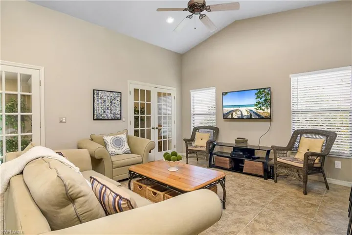 Living room featuring french doors, ceiling fan, high vaulted ceiling, baseboards, and light tile patterned floors