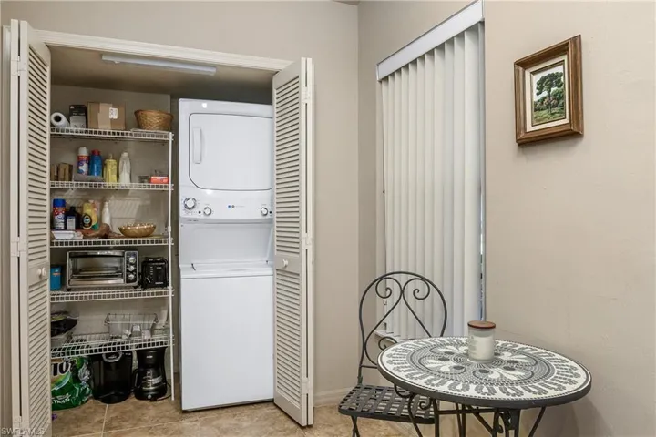 Clothes washing area with stacked washer and clothes dryer and tile patterned floors