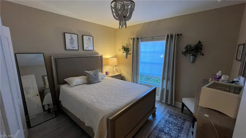 Bedroom featuring dark wood-type flooring and a notable chandelier