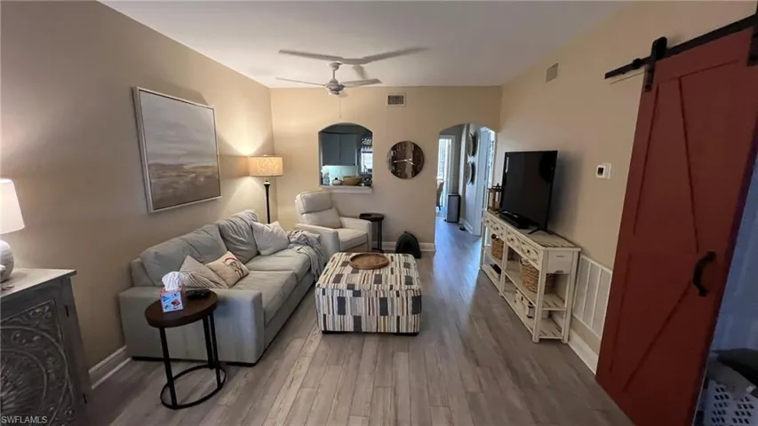 Living room with a barn door, ceiling fan, and hardwood / wood-style flooring