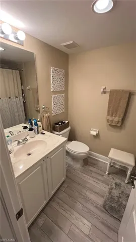 Bathroom featuring toilet, vanity, a shower with shower curtain, and hardwood / wood-style flooring