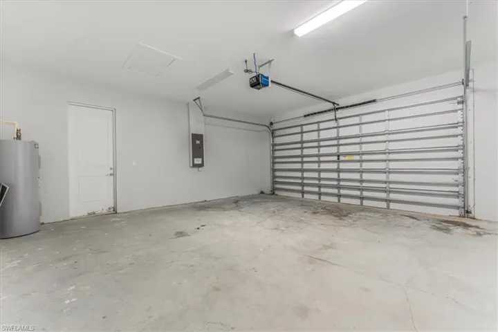 Garage featuring gas water heater, a garage door opener, and electric panel