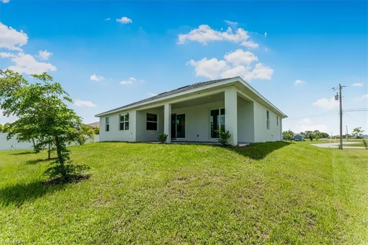 Back of house featuring stucco siding and a yard