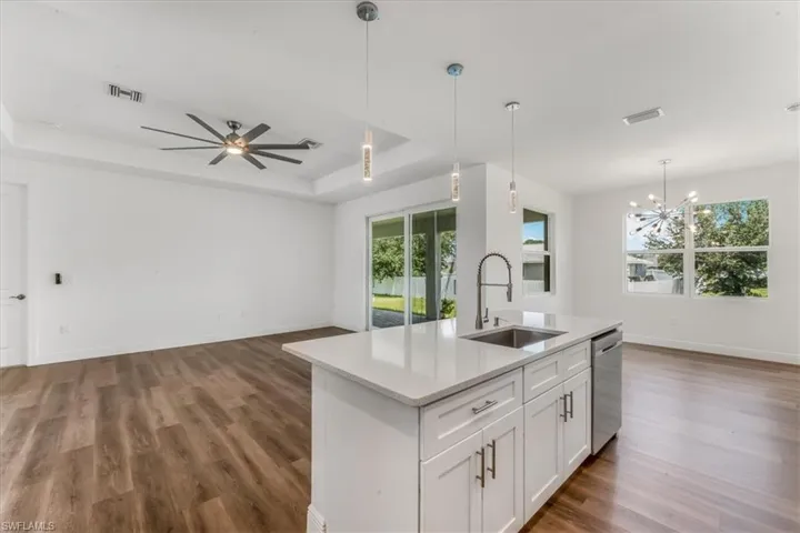 Kitchen with a raised ceiling, open floor plan, wood finished floors, and stainless steel dishwasher
