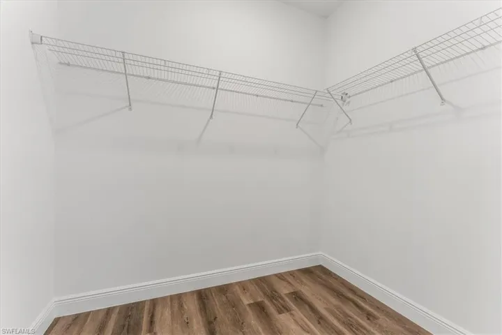 Walk in closet with dark wood-style floors