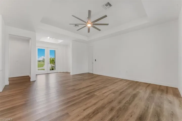 Spare room featuring a raised ceiling, a ceiling fan, and wood finished floors