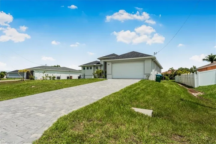Ranch-style house with decorative driveway, an attached garage, and stucco siding