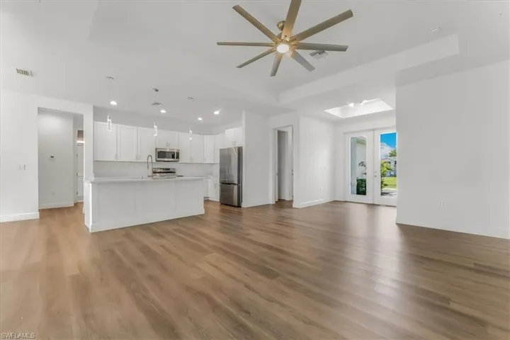 Unfurnished living room with a ceiling fan, wood finished floors, recessed lighting, and french doors