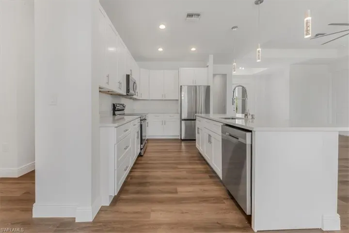 Kitchen featuring appliances with stainless steel finishes, light countertops, recessed lighting, light wood finished floors, and white cabinets