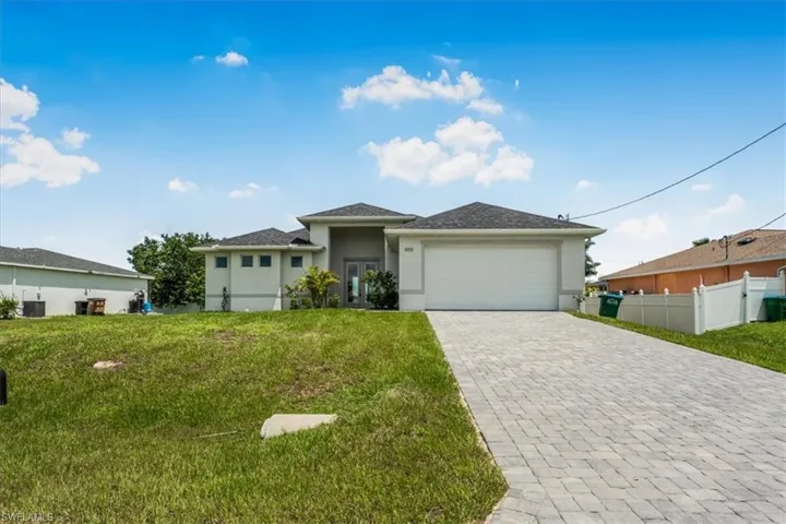 View of front of house featuring stucco siding, a garage, and decorative driveway