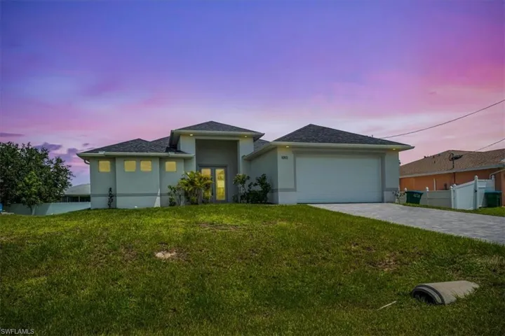 View of front facade with an attached garage, stucco siding, and decorative driveway