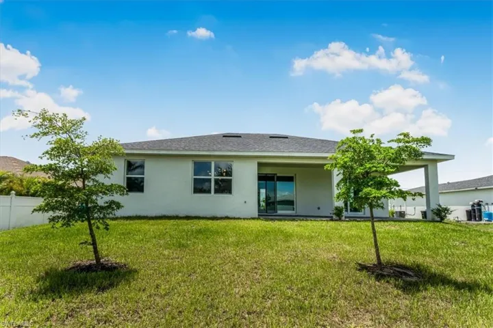 Rear view of house featuring stucco siding and a shingled roof