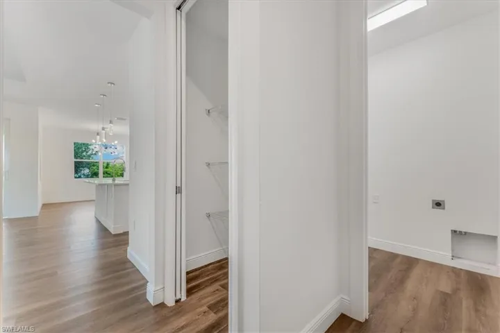 Hall featuring wood finished floors and a chandelier