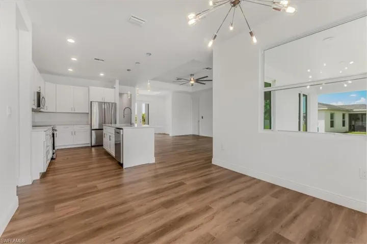 Kitchen featuring appliances with stainless steel finishes, open floor plan, light countertops, a chandelier, and white cabinetry