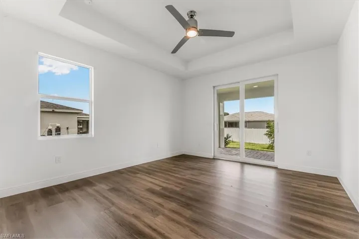 Spare room with a raised ceiling, wood finished floors, and ceiling fan