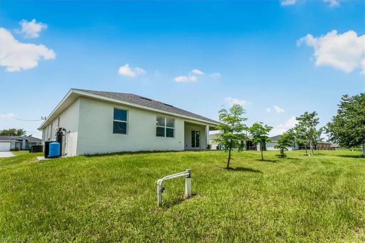 Back of house featuring stucco siding and a yard