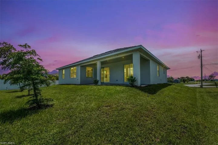 Back of property featuring stucco siding and a yard