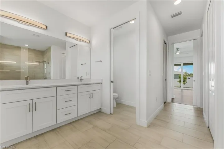 Bathroom featuring a stall shower, double vanity, and a ceiling fan