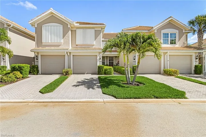 Mediterranean-style townhome featuring an attached two-car garage, barrel tile roof, and stucco exterior