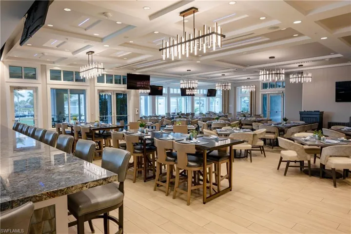 Spacious dining area featuring wood-finish flooring, coffered ceilings, and multiple modern chandeliers