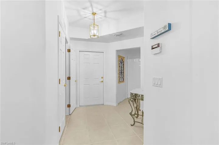 Foyer featuring a paneled entry door, flush-mounted brass lantern light fixture, ceramic tile flooring, and integrated wall switches