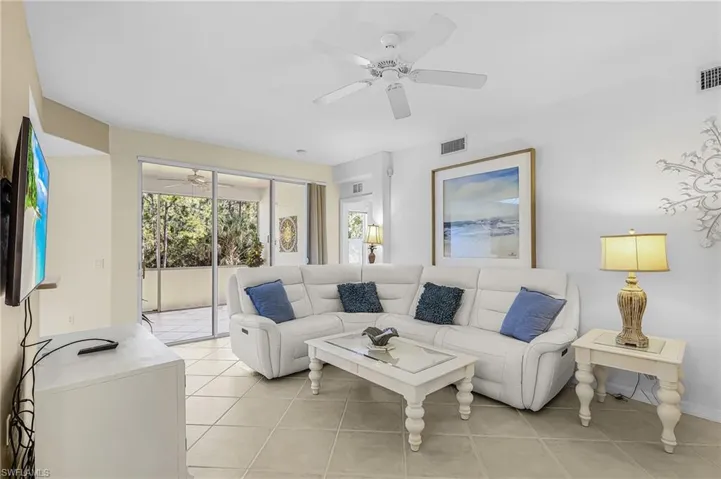 Living area featuring light-toned tile flooring, recessed lighting, and a ceiling fan