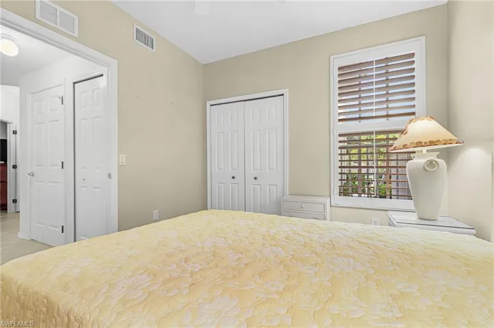 Bedroom with neutral wall tones and a window featuring plantation shutters