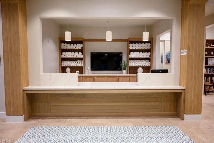 Reception desk featuring a light wood-finish base, white countertop, and three pendant lights