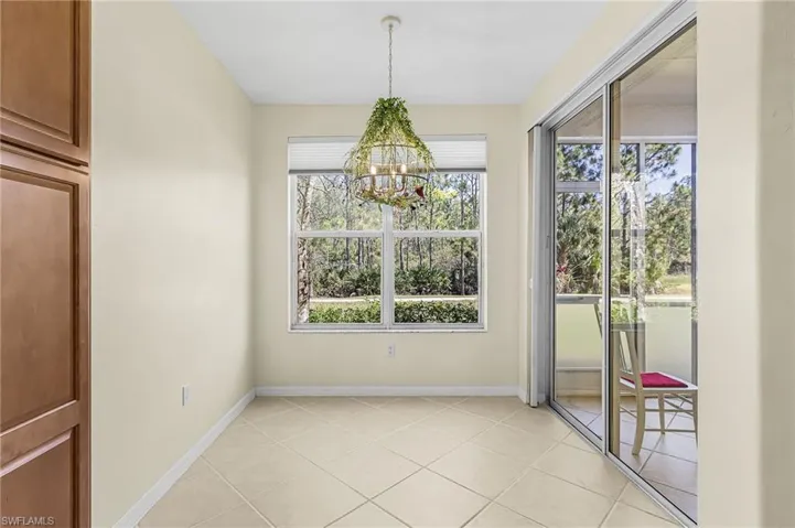 Dining area featuring tile flooring, a large window with privacy blinds, and a sliding glass door opening to an outdoor space