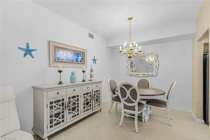 Dining area featuring tile flooring, a brass-finish chandelier, and a decorative wall mirror